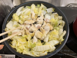白菜に鶏肉を加えて炒める様子
